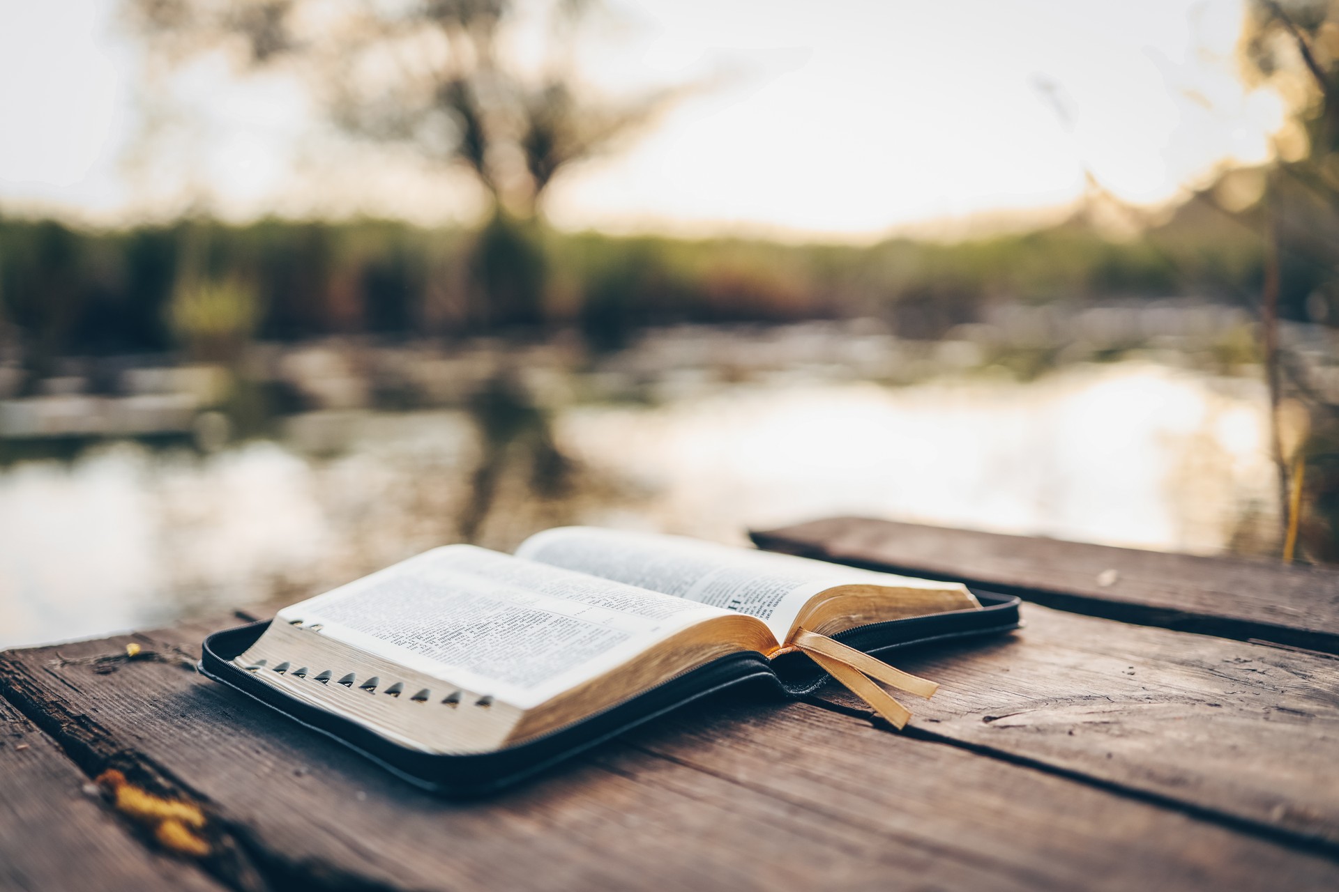 Open Bible on a wooden board near the river